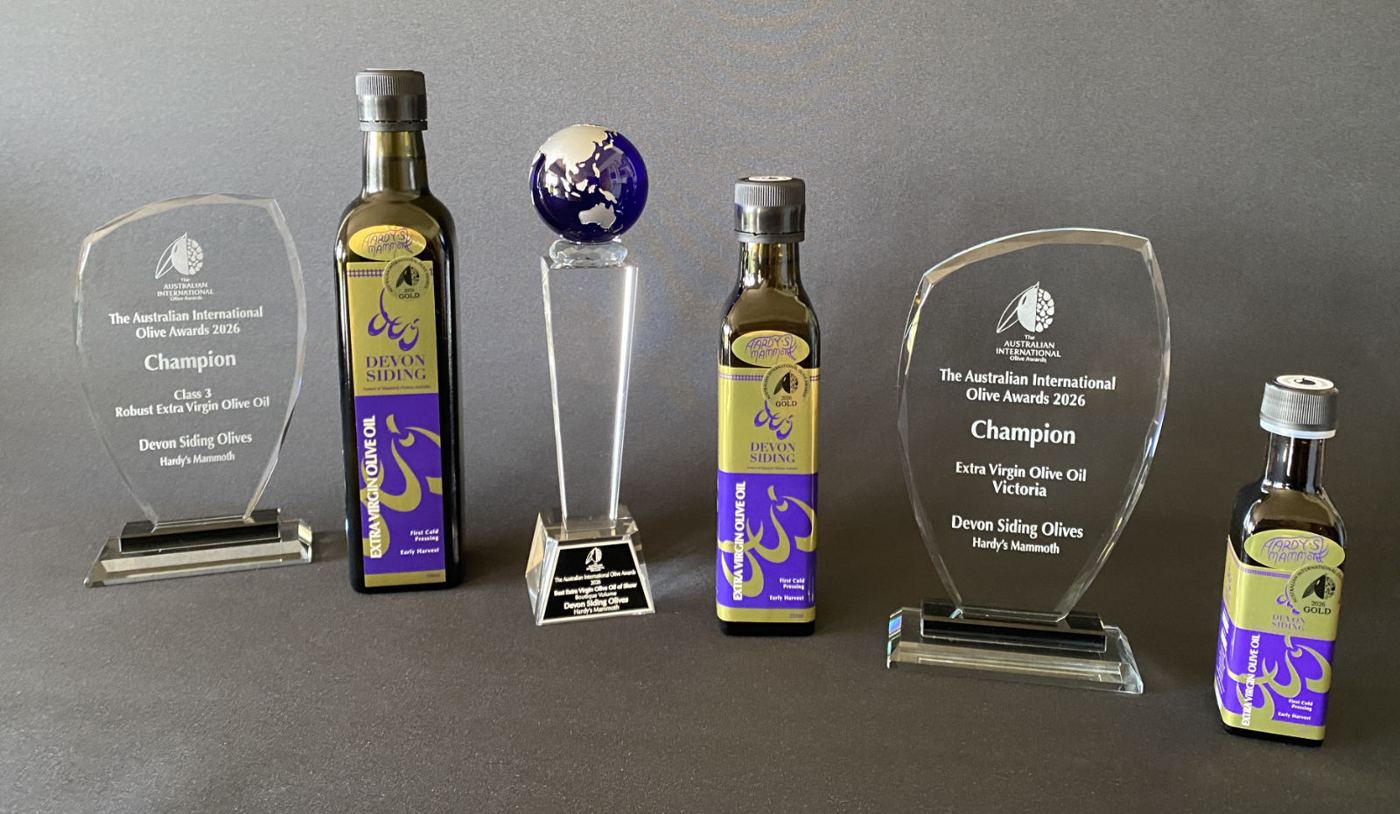 Devon Siding olive oil bottles with their 2026 Australian International Olive Awards trophies